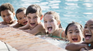 Group of children at edge of pool smiling widely